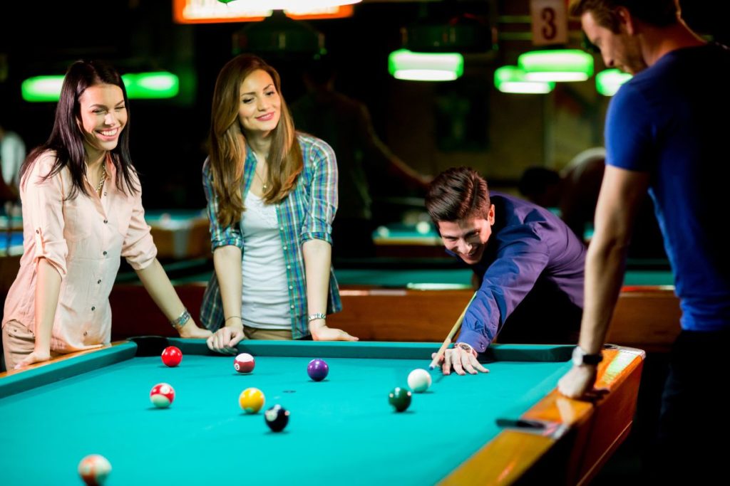 Friends standing around playing pool