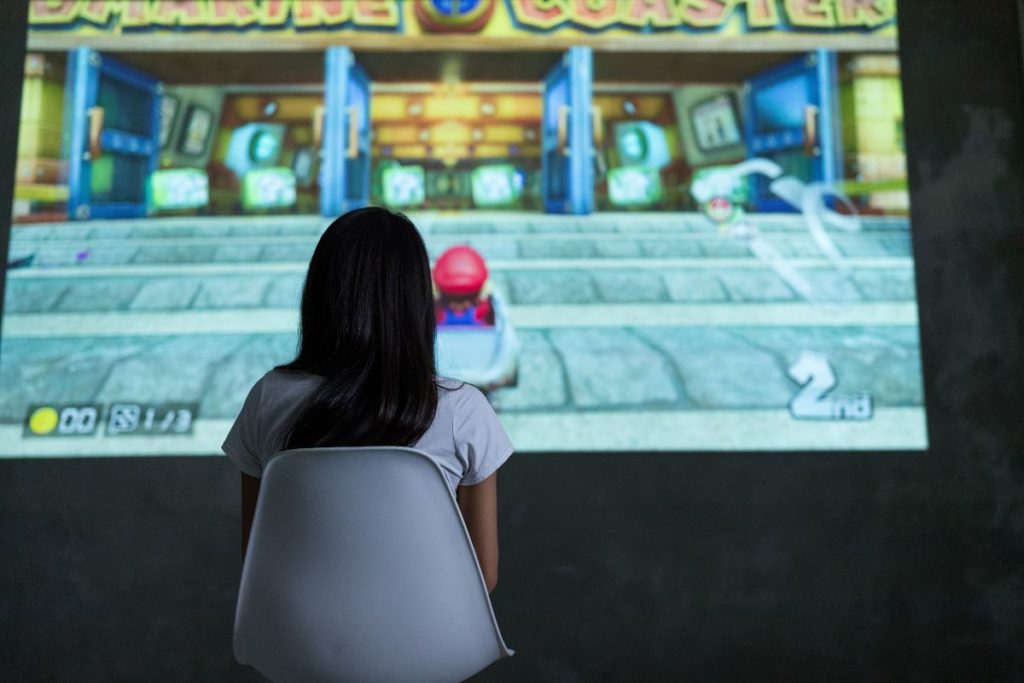 Girl Sitting in a chair playing Mario Kart